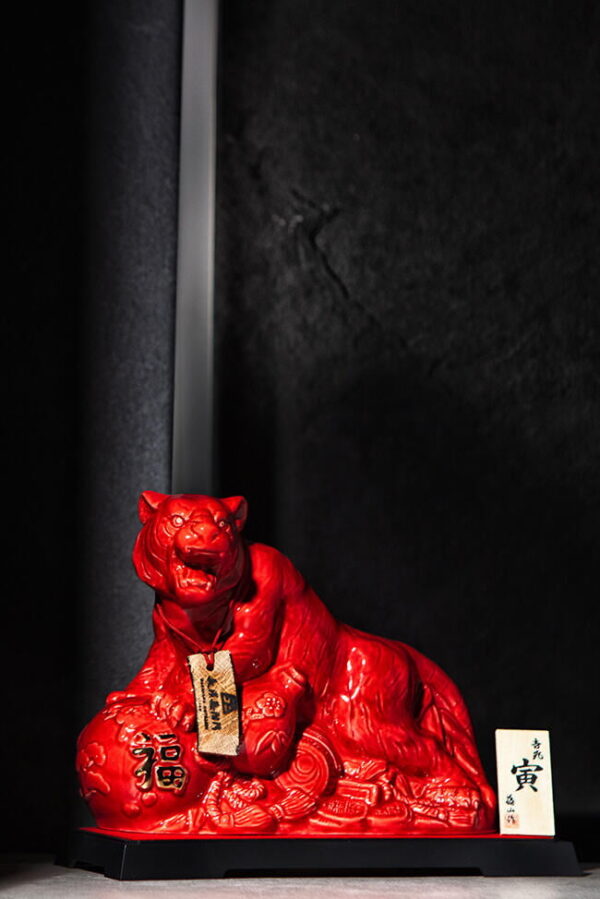 a bottle of a red tiger against a wall in a moody shot