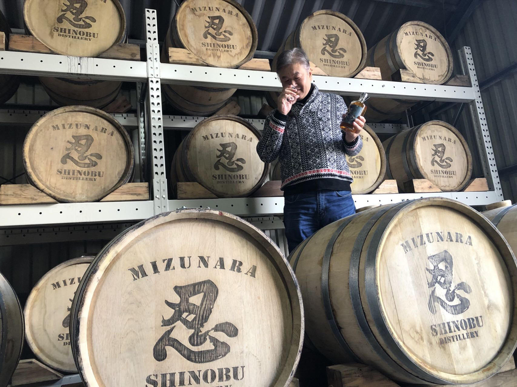 showing Shinobu master blender Ken Usami smelling a glass of Shinobu whisky standing on top of Mizunara cask Shinobu